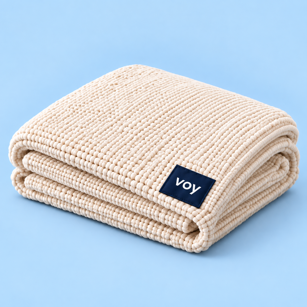 Folded ivory Voy blanket with a navy fabric label on powder blue